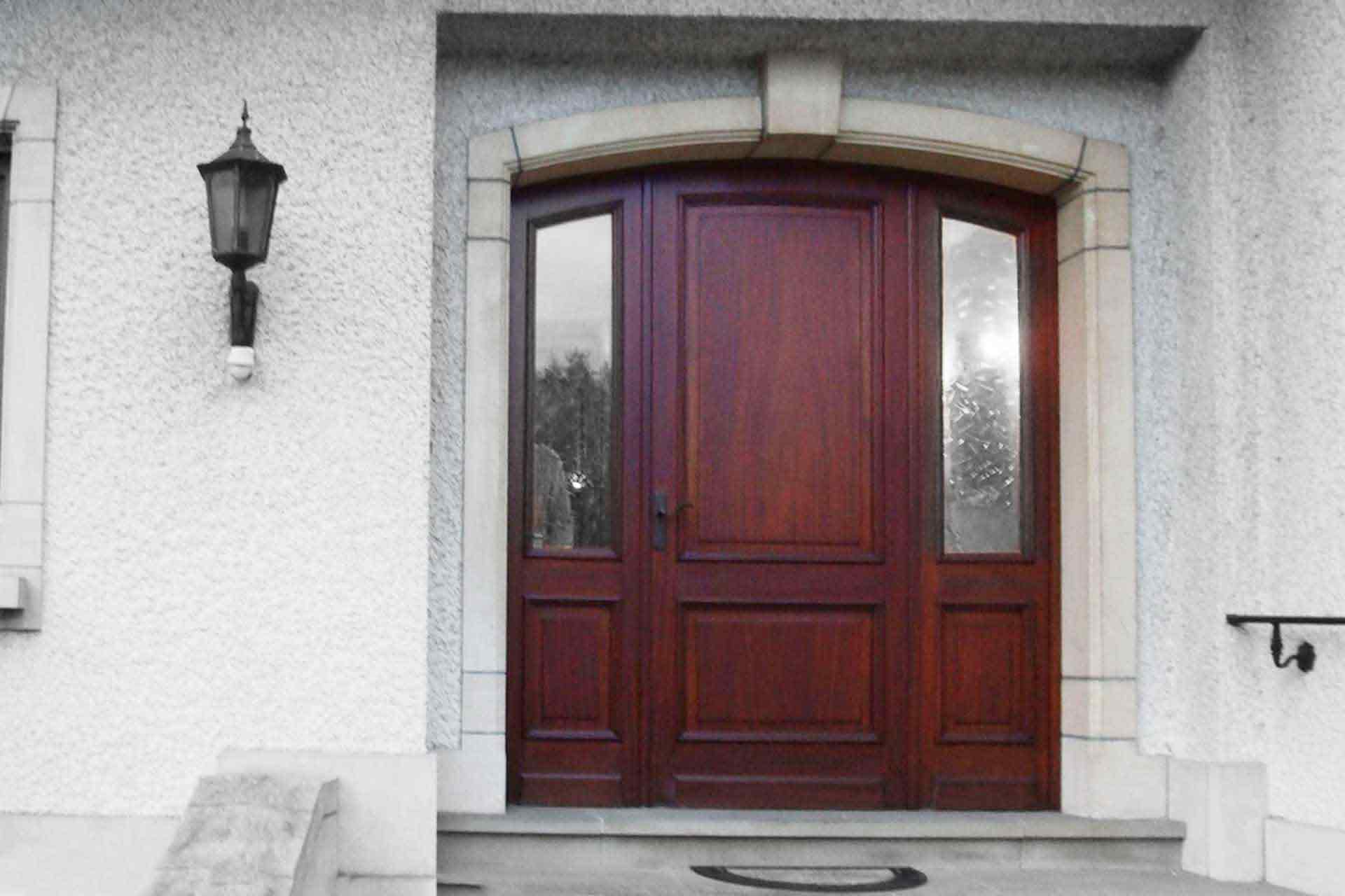 Vorher-Bild. Vor der Modernisierung mit Coplaning Luxemburg. Nahaufnahme des Eingangsbereichs eines weißen Einfamilienhauses mit Blick auf die neue braune Coplaning Haustür.
