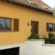 Oranges Einfamilienhaus mit einer brauner Coplaning Haustür mit Glasausschnitten.