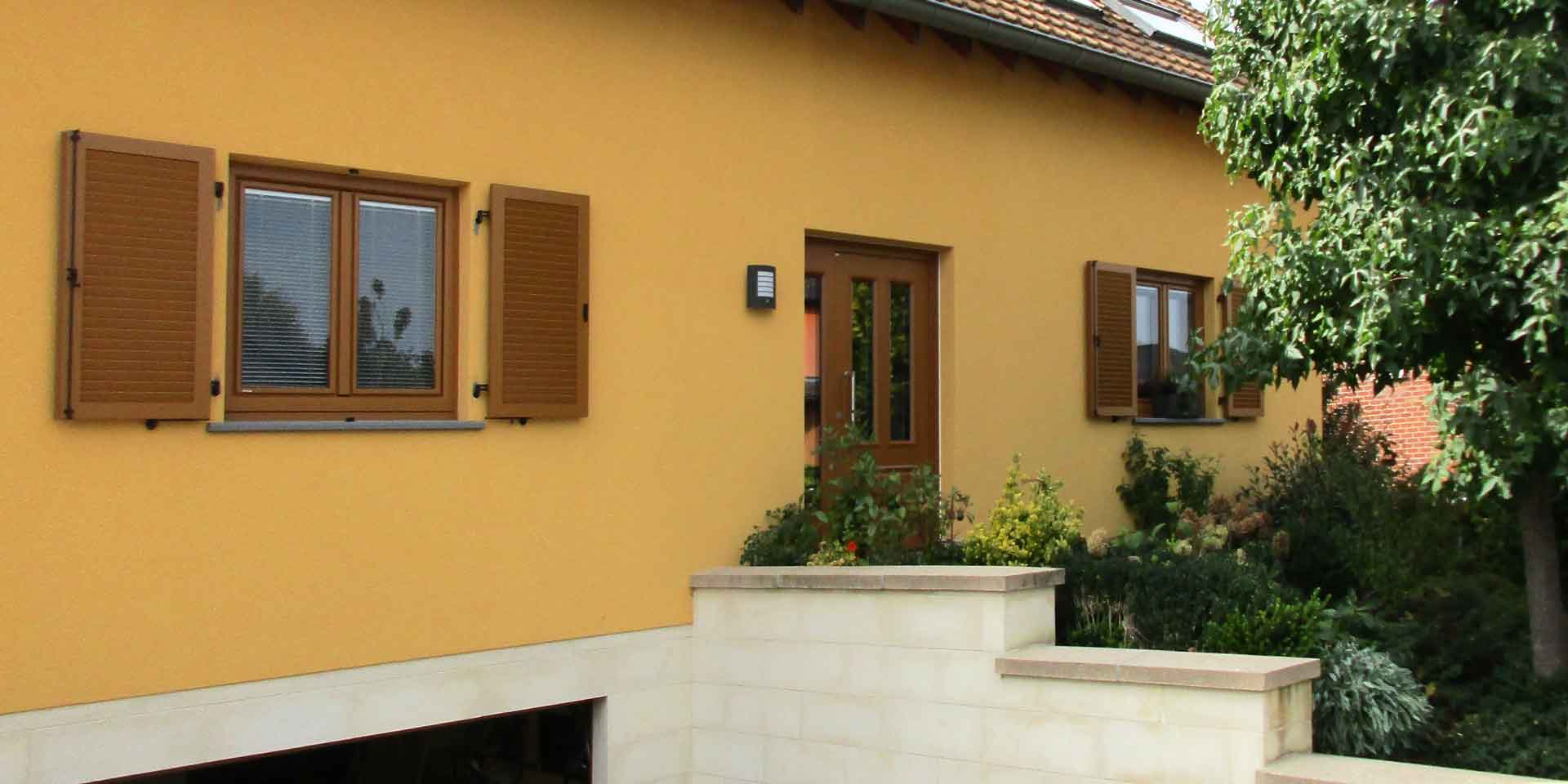 Oranges Einfamilienhaus mit einer brauner Coplaning Haustür mit Glasausschnitten.