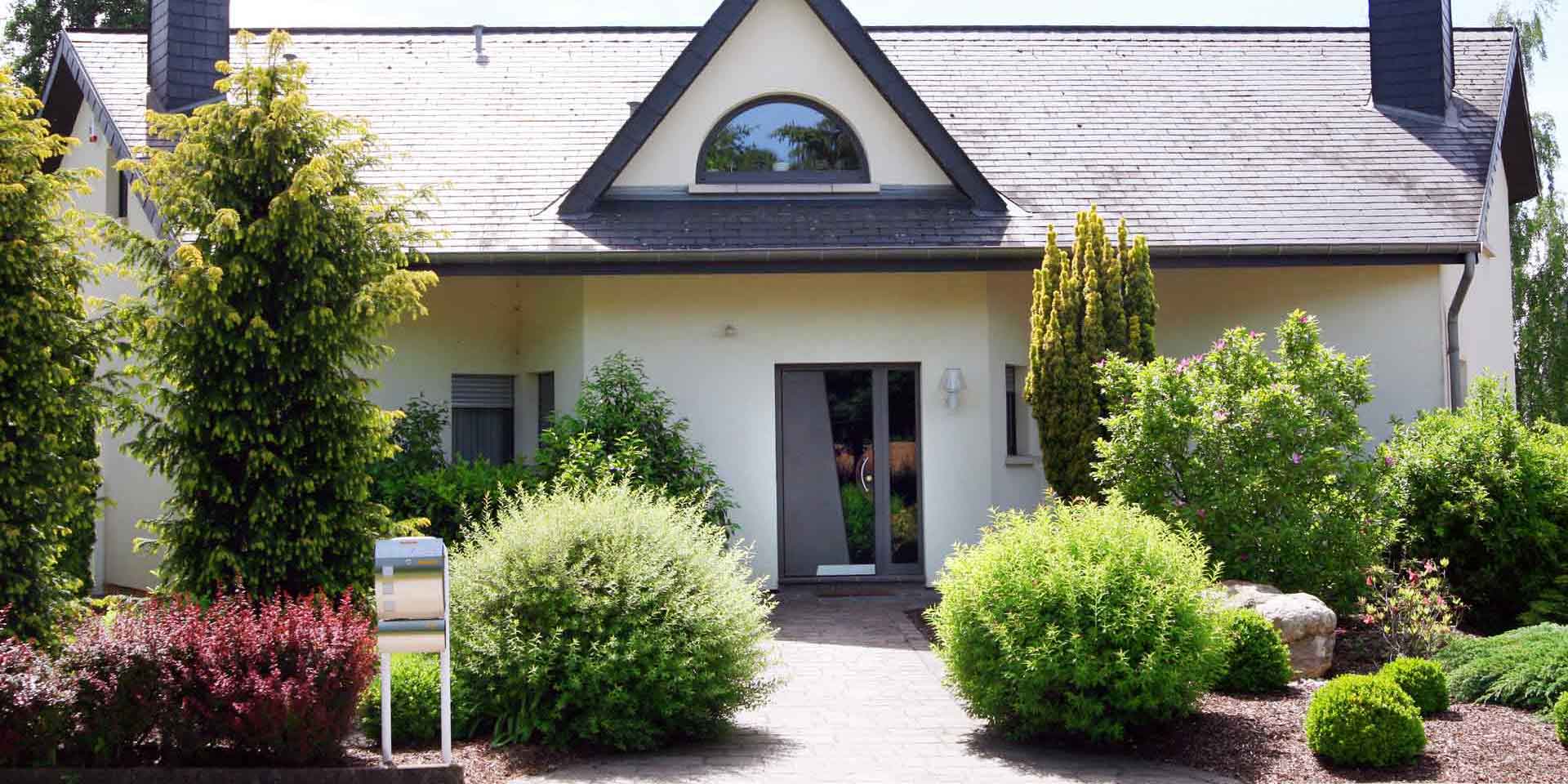 Weißes Einfamilienhaus mit grauer Coplaning Alu Haustür und darüber ein Coplaning Alu Halbkreis Fenster.