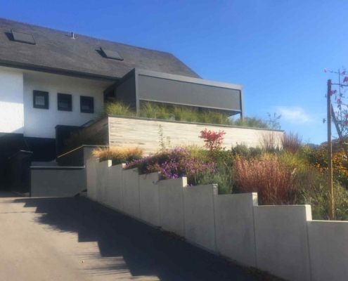 Weißes Einfamilienhaus mit einer Coplaning Veranda QuadratoA mit Terassenüberdachung und einem Lamellendach.