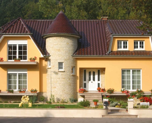 Gelbes Einfamilienhaus mit klassisch weißer Coplaning Haustür und großen weißen Coplaning Fenster.
