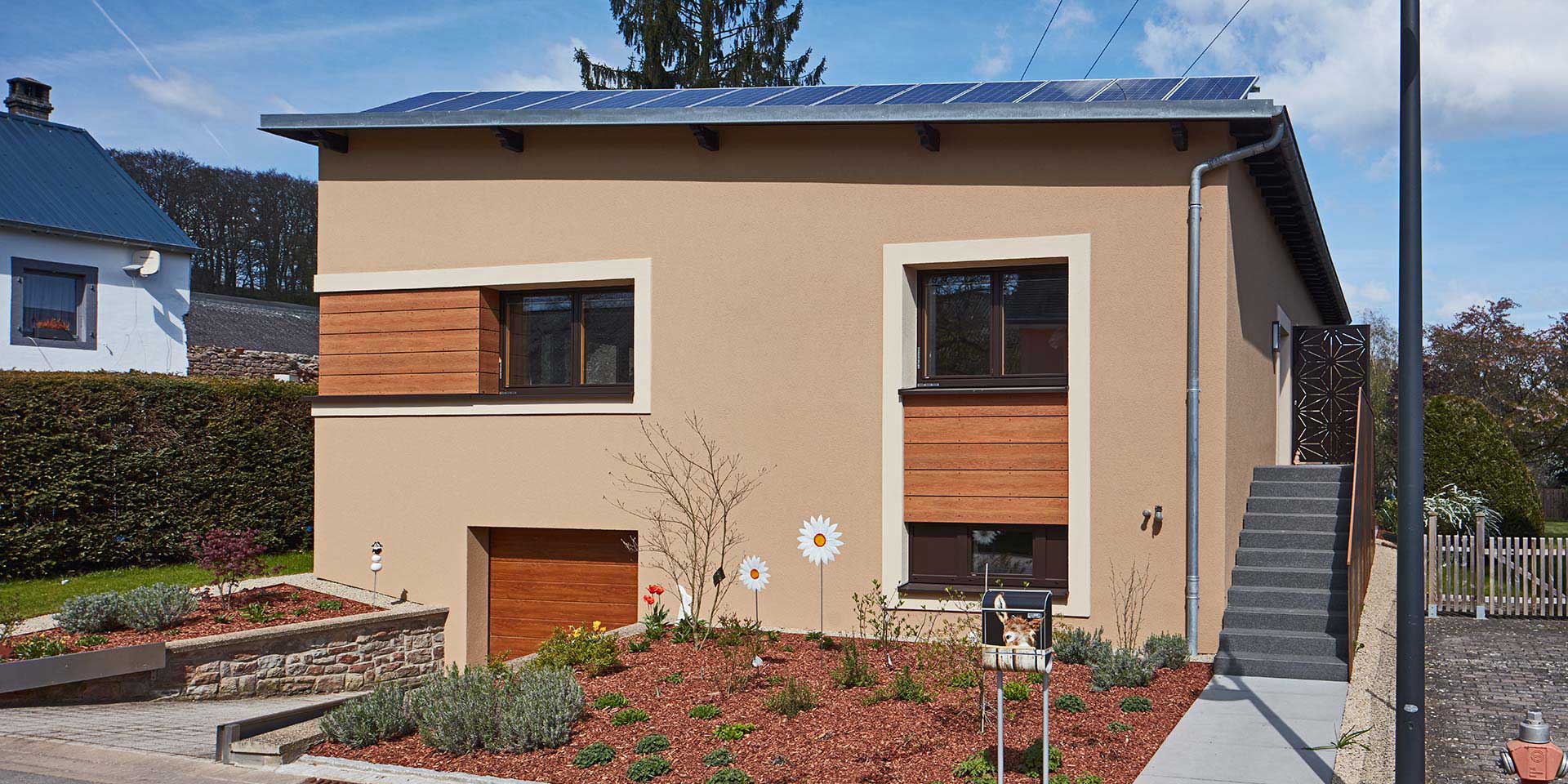 Braunes Einfamilienhaus mit modernen braunen Coplaning Alu Fenster und einem Coplaning Garagentor aus Holz.