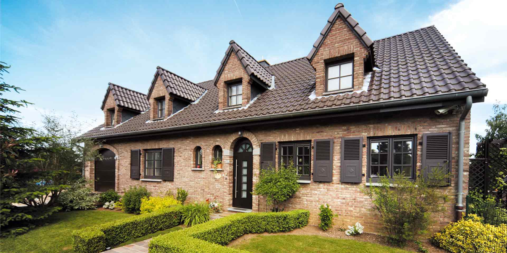 Einfamilienhaus mit Steinfassade mit brauner Coplaning Rundbogen Haustür und brauen Landhausstil klassischen einbruchsicheren Coplaning Gaubenfenster.