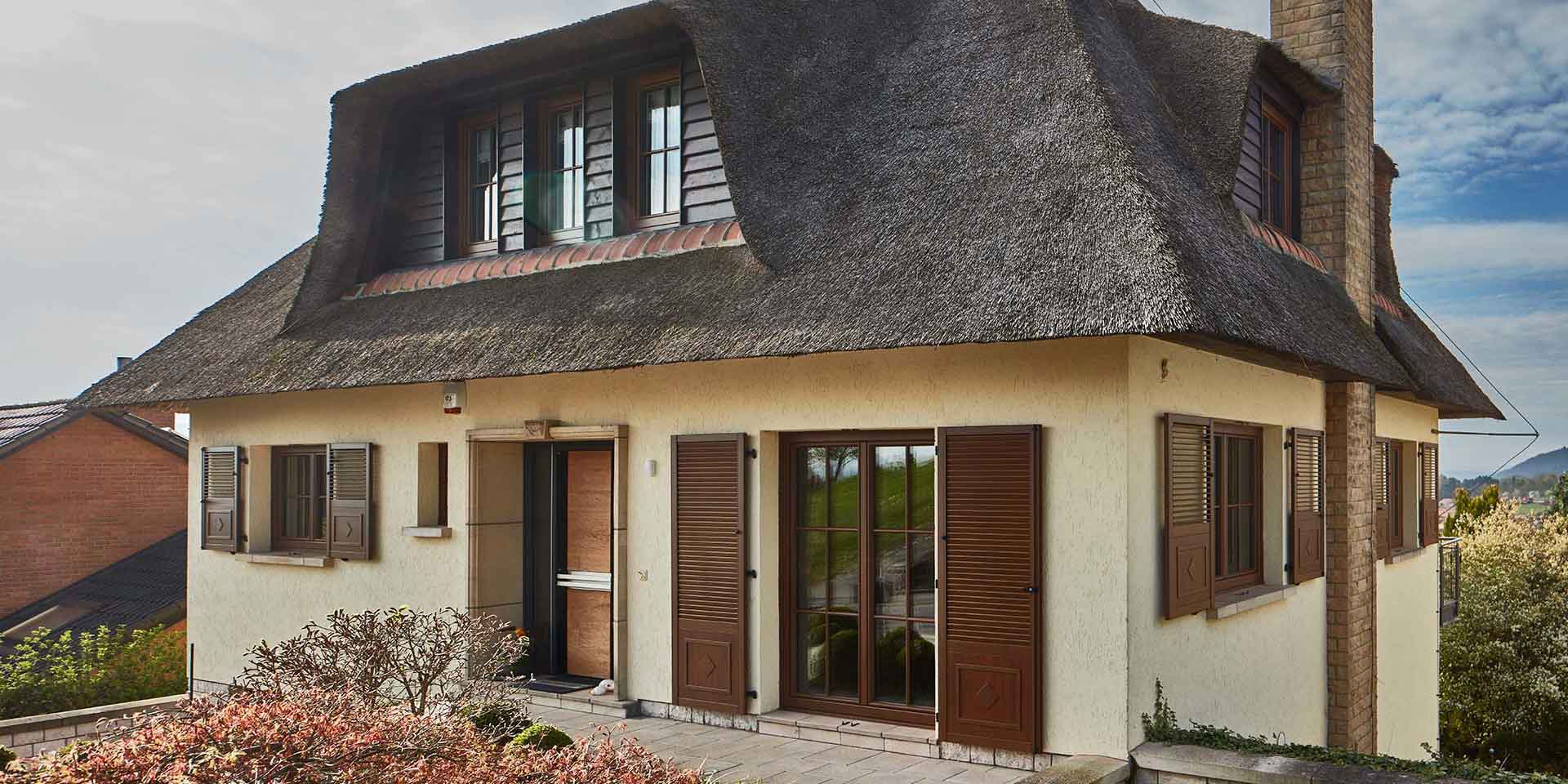 Weißes Einfamilienhaus von rechts gesehen mit moderner Coplaning Holz- Glas Haustür und Coplaning Holz- Alu Fenster.