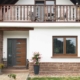 Weiß- braunes Einfamilienhaus mit braun-grauer Coplaning Haustür und Holz Alu Coplaning Fenstern.