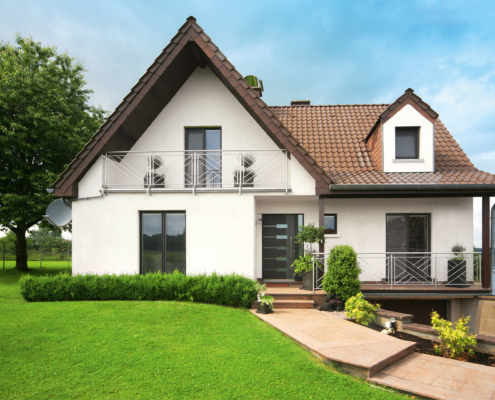 Vorderseite eines weißen Einfamilienhaus mit neuer moderner Coplaning Haustür und modernen Coplaning Alufenster.