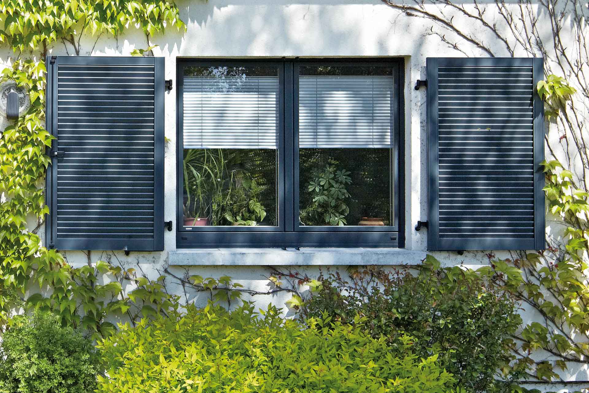 Nahaufnahme eines weißen Einfamilienhauses mit Blick auf ein graues modernes Holz- Alu Coplaning Fenster.