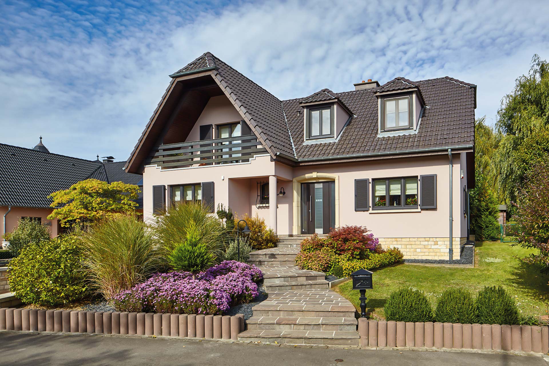 Leicht pinkes Einfamilienhaus mit einer grauen Coplaning Alu Haustür und grauen Coplaning Holz- Alu Fenster mit passenden Klappläden.