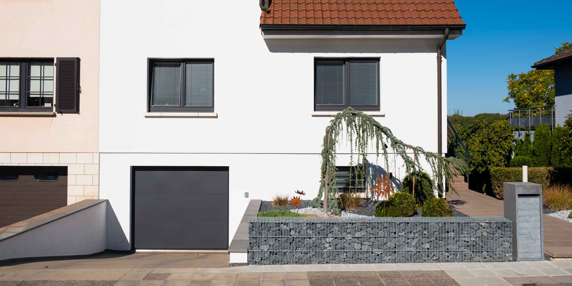 Weißes Einfamilienhaus mit grauen Coplaning Holz-Alu Fenster.