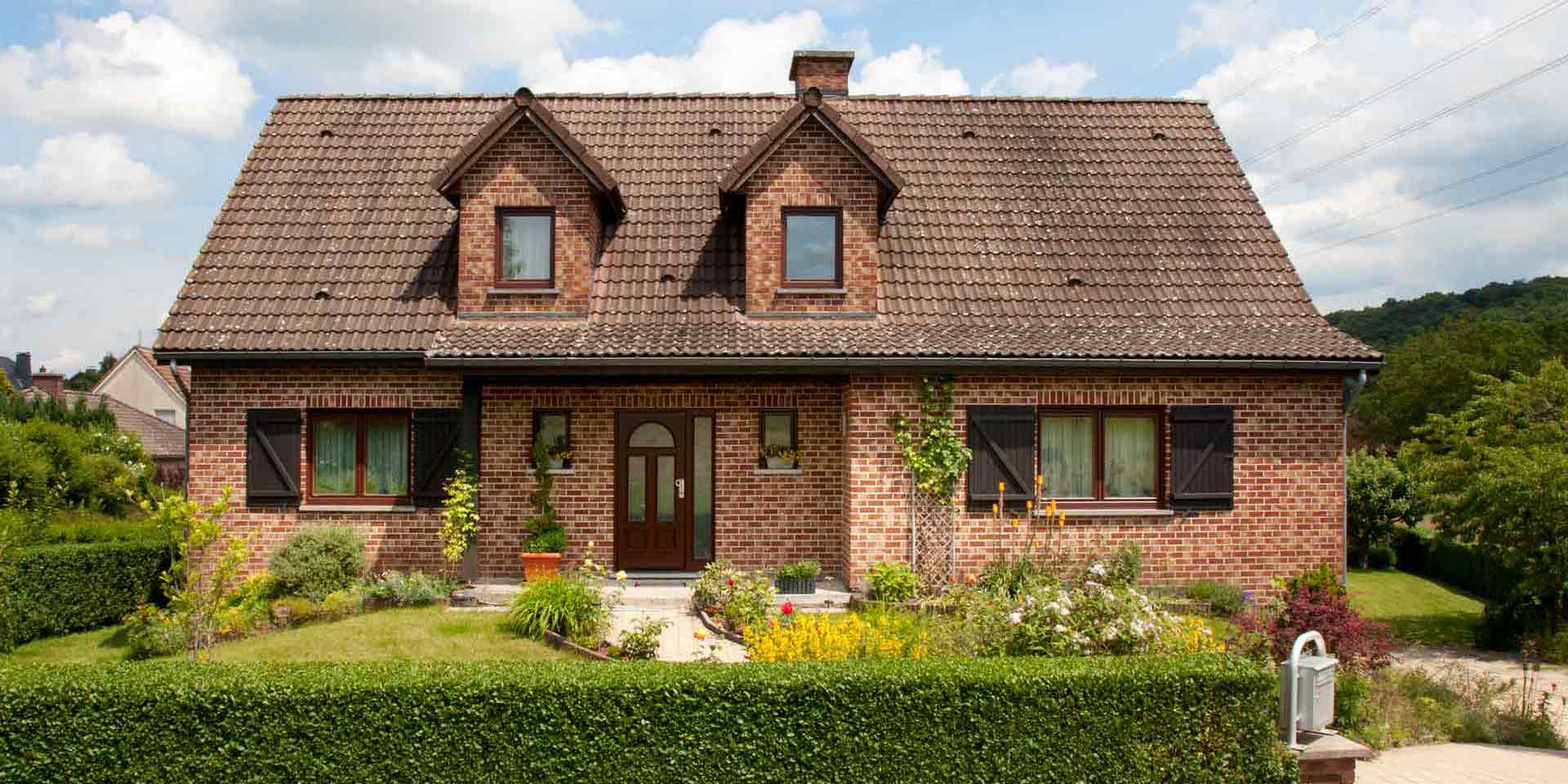 Einfamilienhaus mit Klinkerfassade mit einer braunen klassischen Coplaning Haustür und braunen Coplaning PVC Alu Fenster.