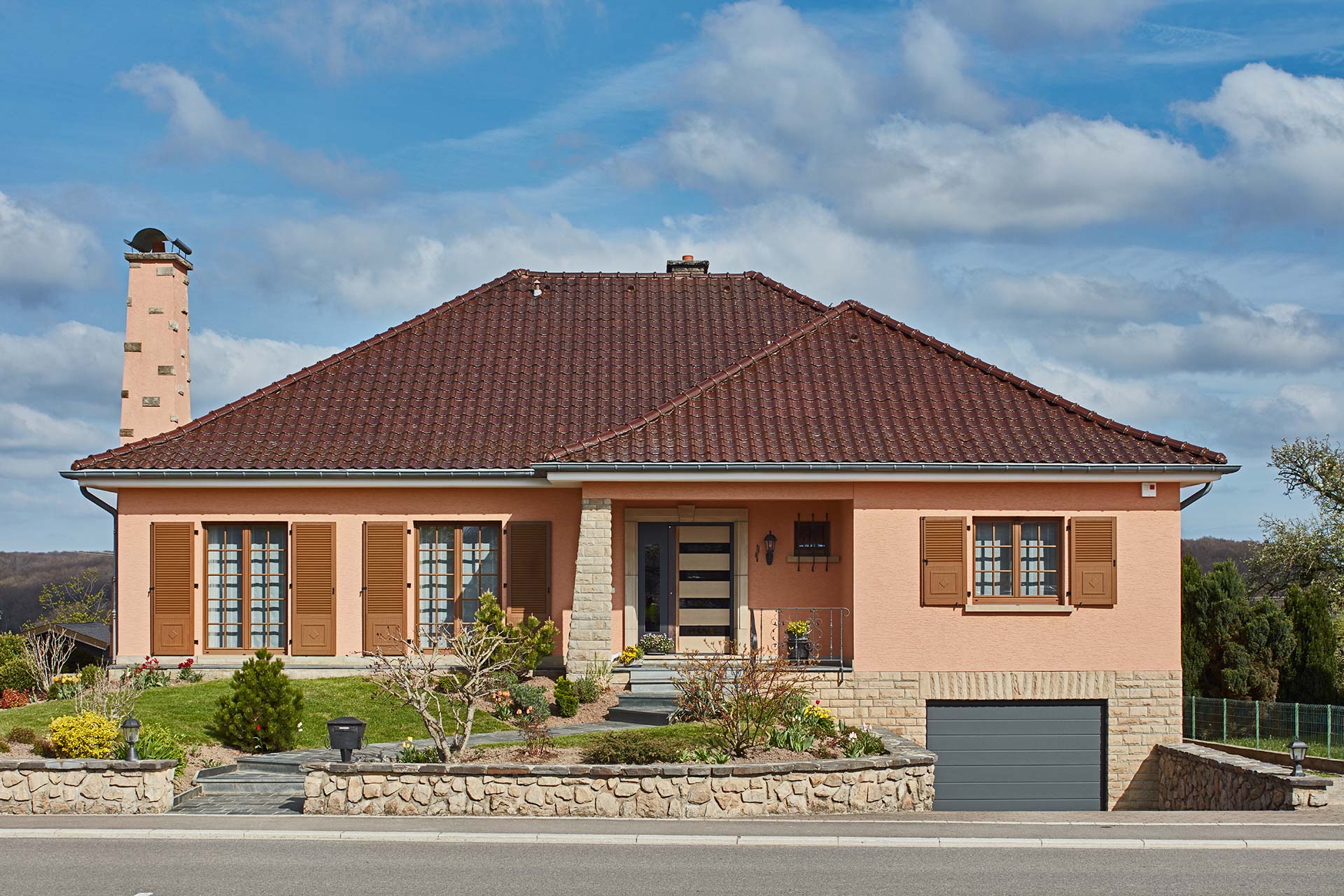 Modernisierung eines orangen Einfamilienhaus mit neuer moderner grau-keramik Coplaning Haustür und braunen modernen Fenster mit Klappläden.