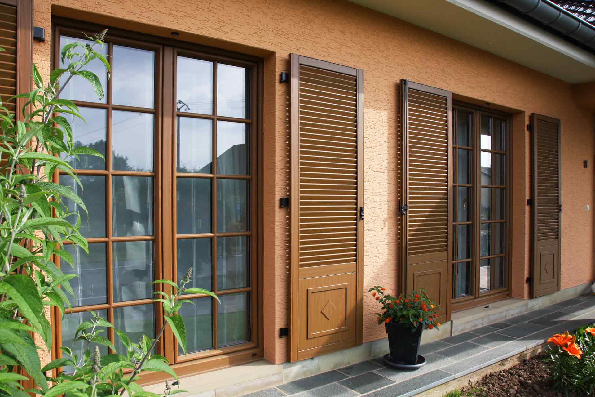 Nahaufnahme von zwei Coplaning Fenster mit Klappläden von dem orangen Einfamilienhaus.