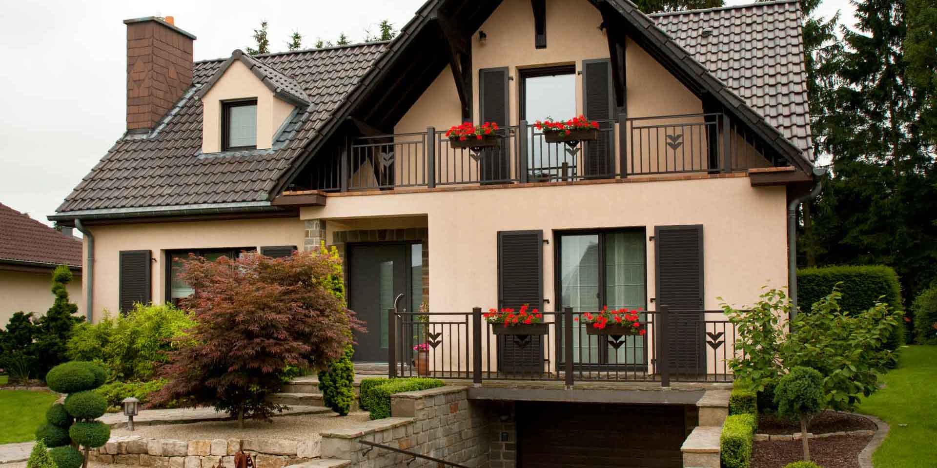 Leicht pinkes Einfamilienhaus mit einer braunen Coplaning Alu Lack Haustür, braunen Coplaning Alu Fenster mit braunen Alu Klappläden.