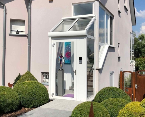 Weißes Einfamilienhaus mit Nahaufnahme einer weißen Coplaning Alu- Überdachung des Eingangsbereichs mit Treppen.
