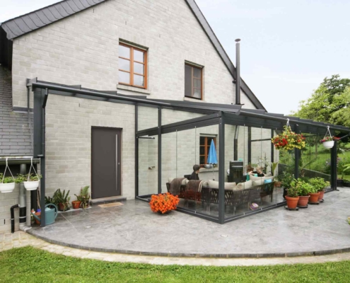 Graues Einfamilienhaus mit einer grauen Coplaning Aluminium Veranda Glasfaltwand mit Terassenüberdachung.