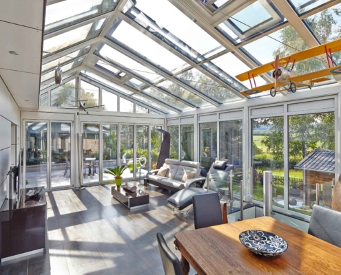 Einfamilienhaus mit Steinfassade mit Nahaufnahme des inneren Bereichs des Coplaning Veranda Wintergarten mit hellgrauer Aluminium Faltanlage mit Glasdach.