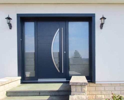 Nahaufnahme des Eingangsbereiches eines weißen Einfamilienhauses mit Blick auf eine graue Coplaning Aluminium Lack Haustür.