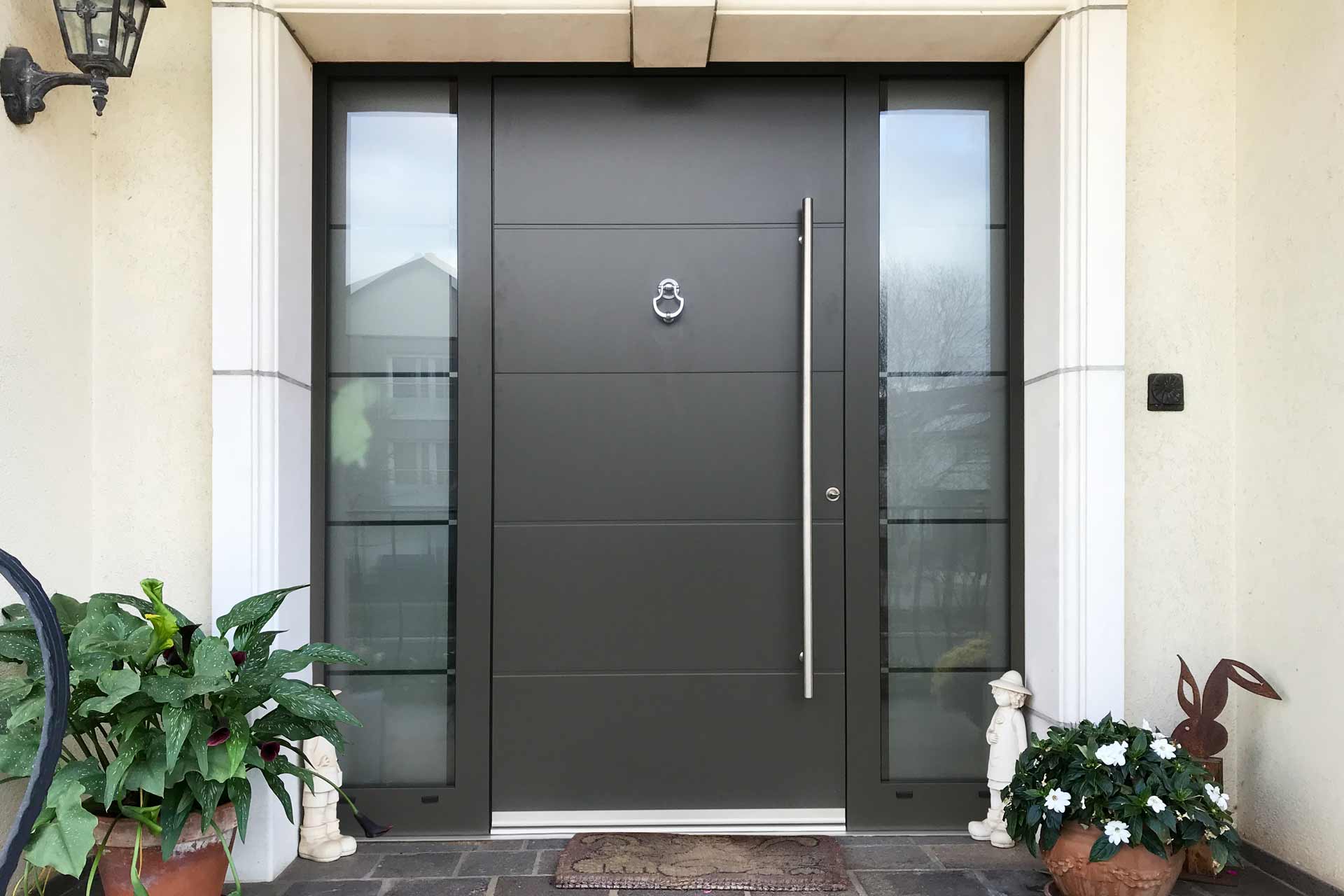Nahaufnahme des Eingangsbereichs mit Blick auf die graue Coplaning Aluminium Haustür mit Türklopfer.