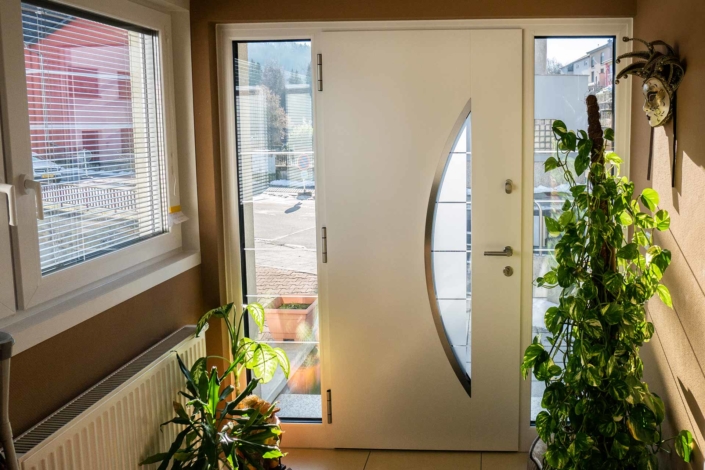 Nahaufnahme von der modernen grau-weißen Aluminium Coplaning Haustür des weißen Einfamilienhauses von innen.