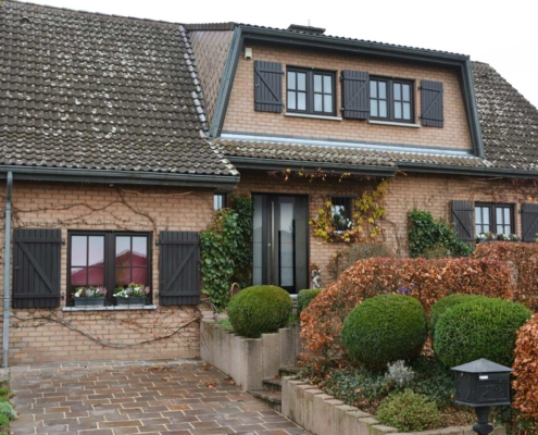 Einfamilienhaus mit Steinfassade mit einer grauen Coplaning Keramik Haustür.